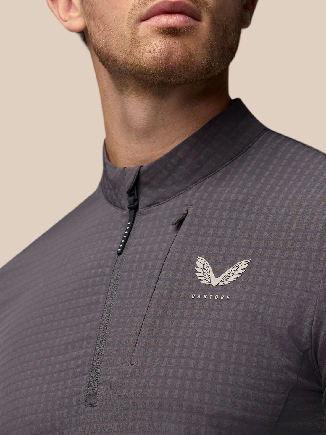 Detail view of the grey Golf 1/2 Zip Top with front zipper and Castore crest on the chest
