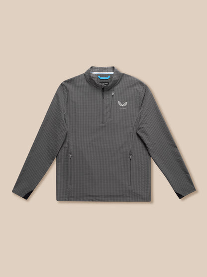 Grey golf top with stand collar and half zip shown on beige background with Castore logo on chest