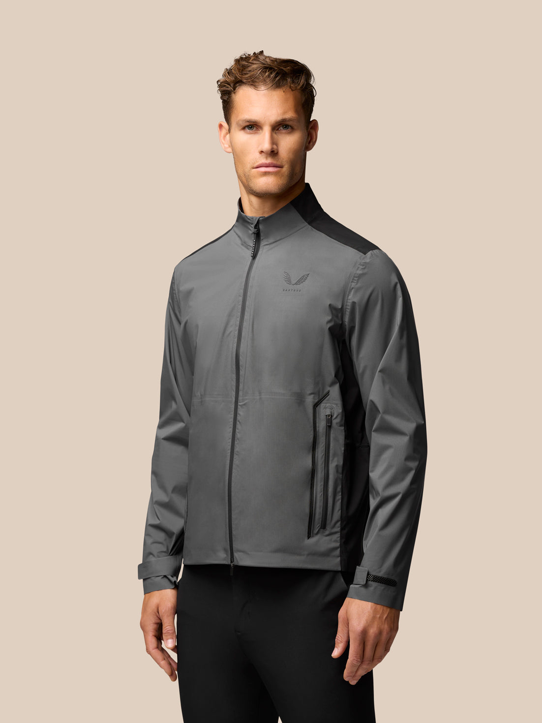 Model wearing gunmetal golf waterproof jacket with stand collar and zip pockets