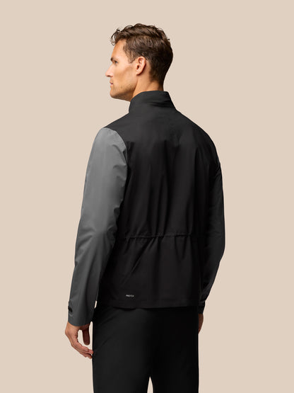 Back view of grey and black two tone golf waterproof jacket on model