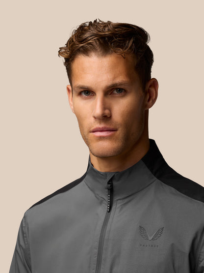 Close-up of a man wearing the Gunmetal Golf Waterproof Jacket showing the chest logo and high collar.
