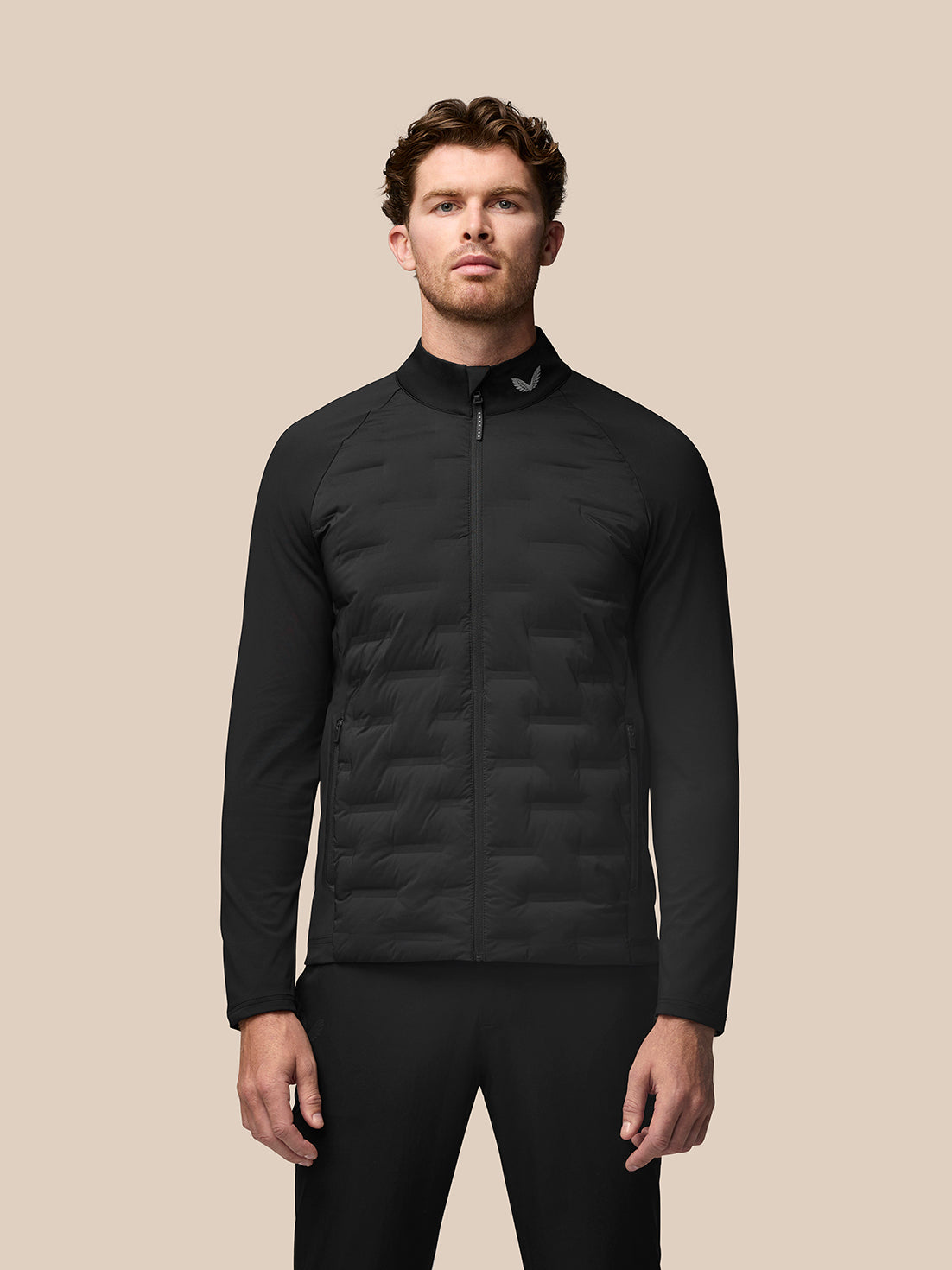 Male model wearing black Golf Pinnacle Jacket with quilted front panels and stand collar