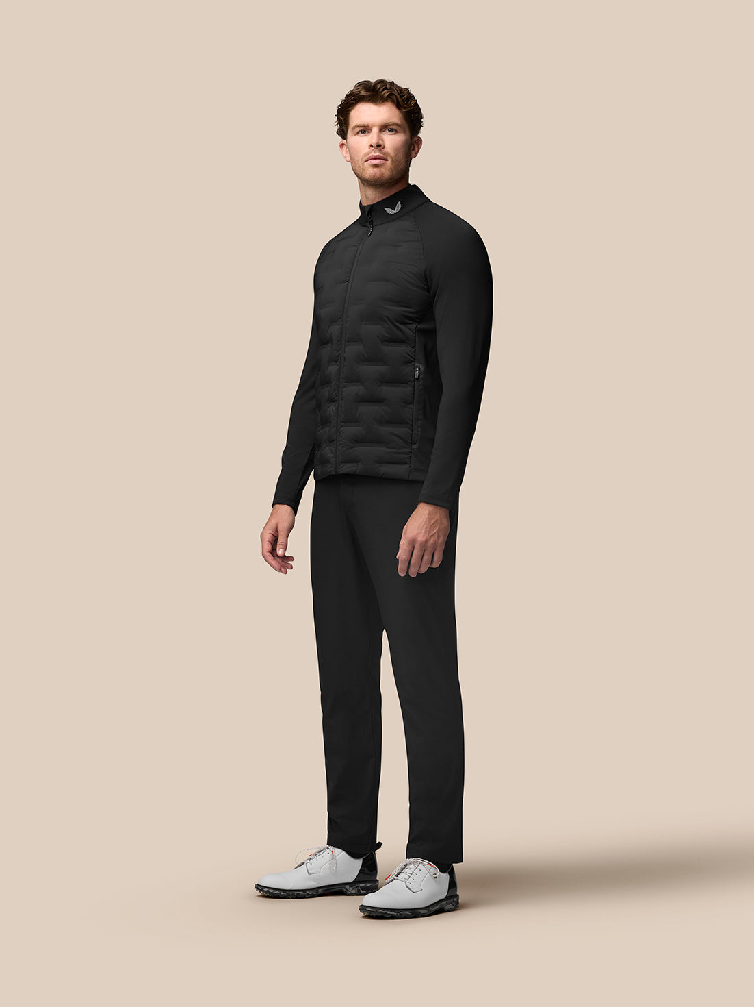 Model wearing black Pinnacle Golf Jacket with quilted front panels and stand collar