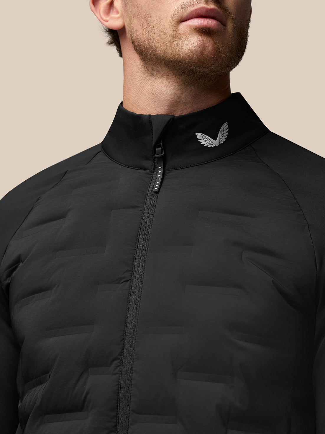 Close up of collar and front zipper on black Golf Pinnacle Jacket with Castore emblem on the collar