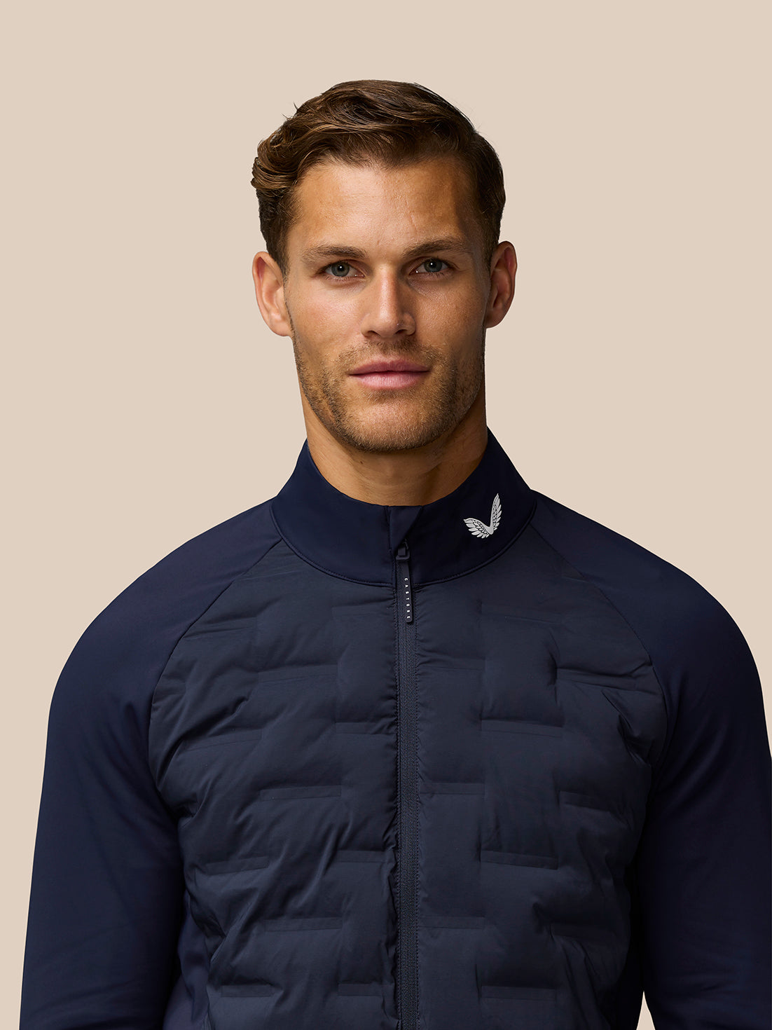 Close up of navy Golf Pinnacle Jacket chest showing zip front and white logo on collar