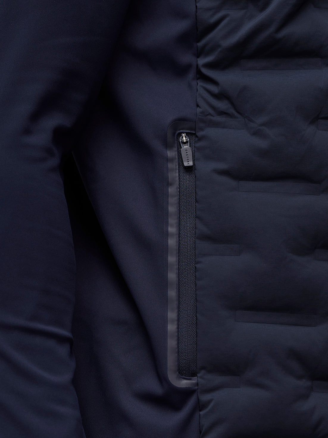 Close up of navy Pinnacle Jacket zipper along a pocket with auto lock puller