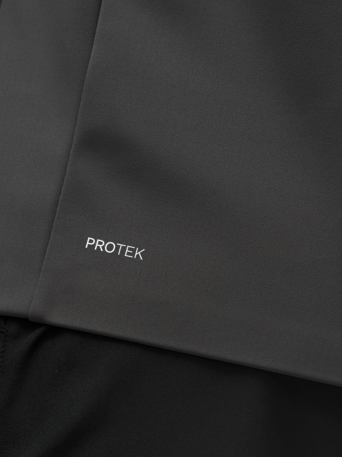 Close-up of the Garcia Hybrid Jacket fabric in charcoal with PROTEK branding.