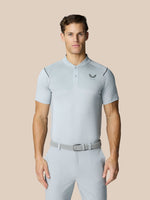 Male model in light grey Pinnacle Golf LVS Polo with diagonal pattern and left chest logo, paired with matching light trousers and belt.