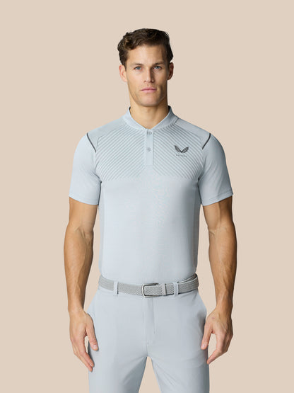 Male model in light grey Pinnacle Golf LVS Polo with diagonal pattern and left chest logo, paired with matching light trousers and belt.
