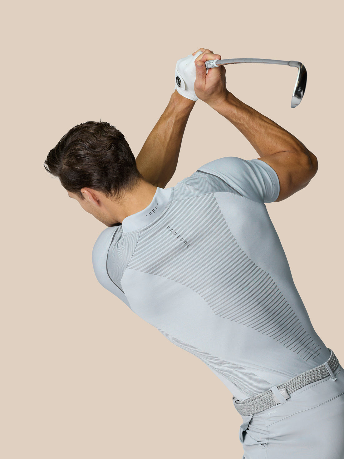 Golfer in mid grey Pinnacle Golf LVS Polo during a swing with back diagonal stripe panels visible