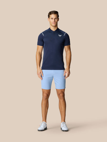 Male model wearing Pinnacle Golf LVS Polo in navy with vented chest panels paired with light blue shorts.