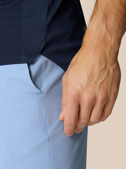 Close-up side view of navy Pinnacle Golf LVS Polo highlighting knit texture and side split hem