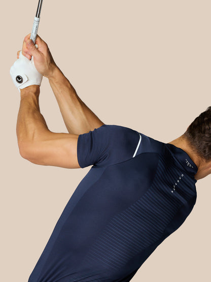 Male model in navy Pinnacle Golf LVS Polo preparing for a swing, showing engineered knit ventilation and side seams