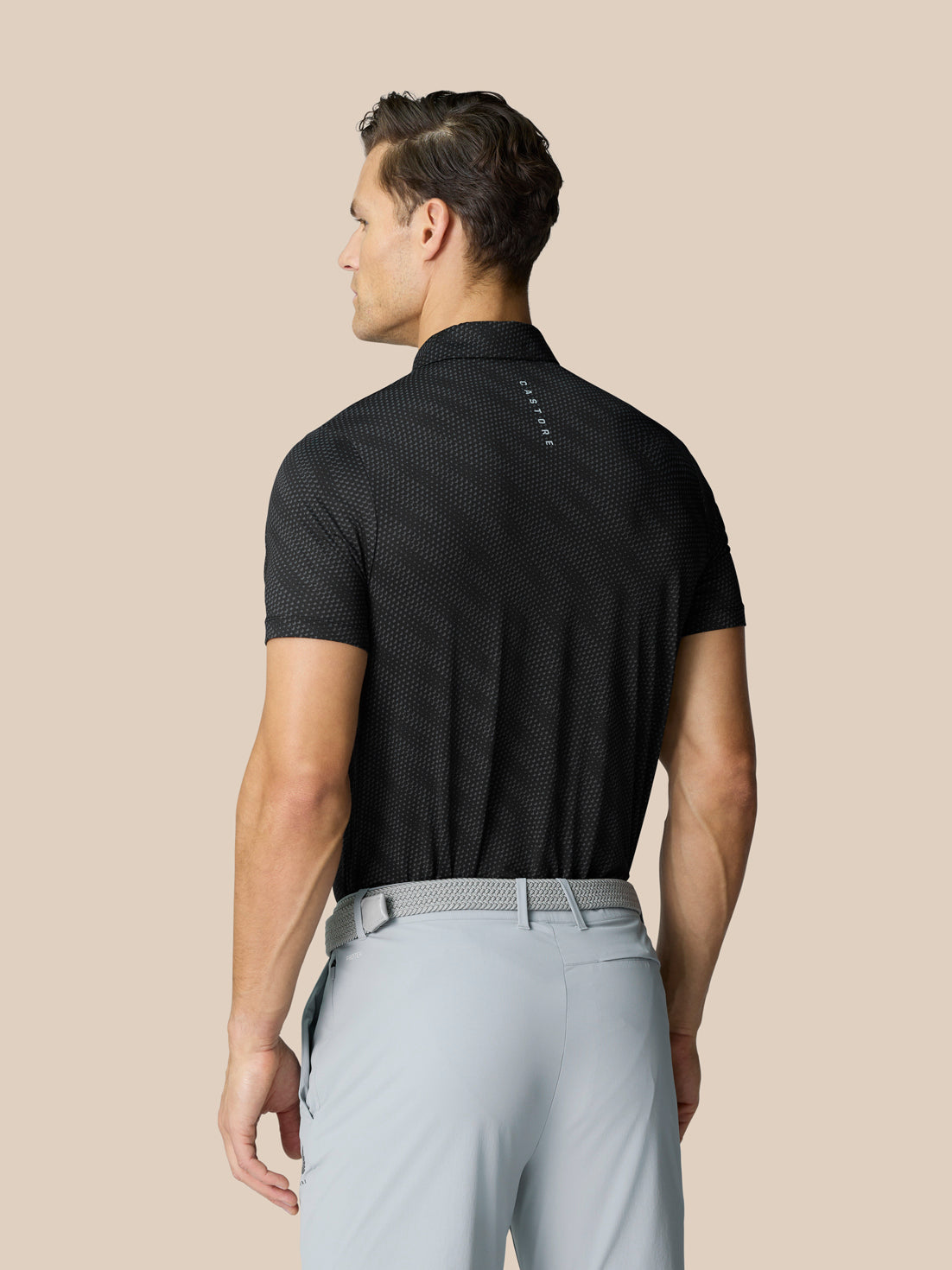 Back view of black Club Graphic Polo showing dotted pattern and vertical Castore branding on the upper back.