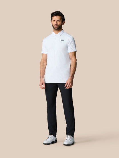 Full-body front view of a male model wearing a light textured polo shirt with Castore logo on the chest and black pants.