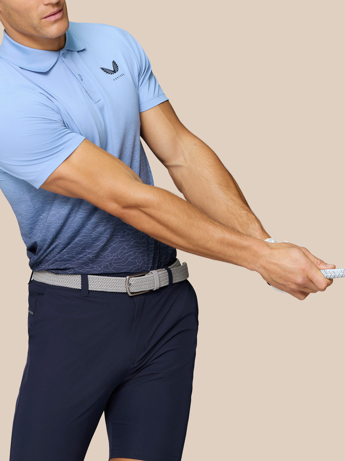 Male model wearing Club Graphic Polo in sky blue gradient with an ombre pattern and left chest Castore logo, mid swing with a golf club.