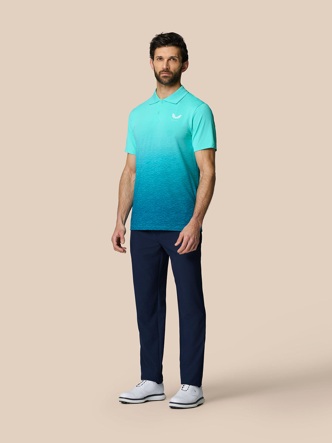 Full model wearing Club Graphic Polo Light Aqua with gradient ombre pattern left chest logo, navy pants and white shoes.