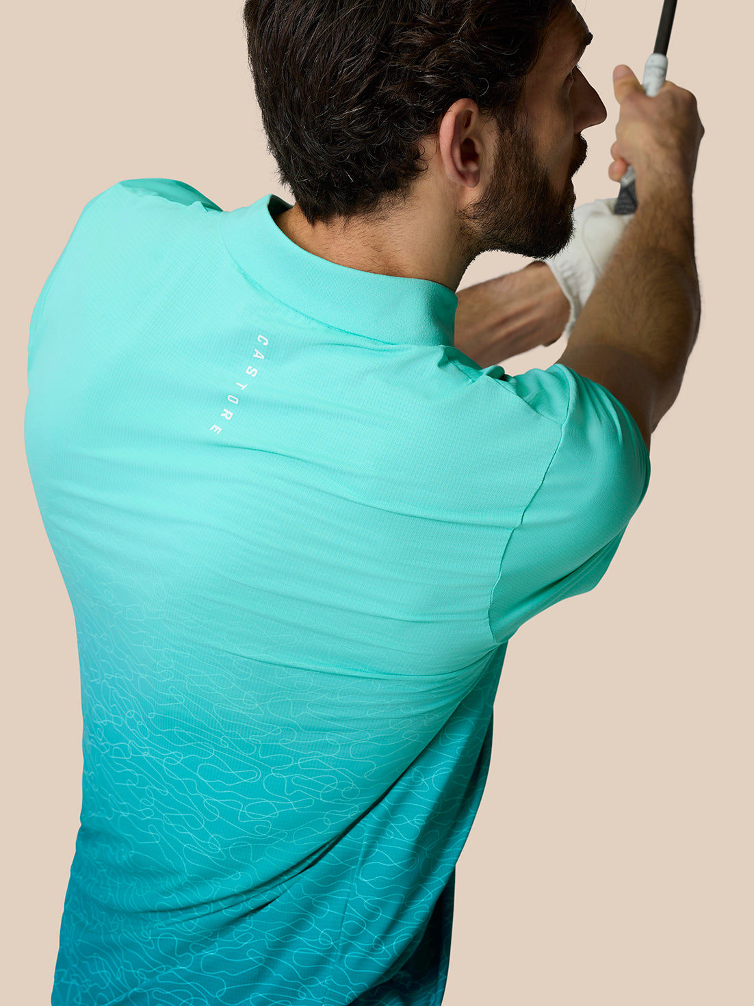 Back view of a man wearing a light aqua Club Graphic Polo with ombre pattern and Castore branding on the upper back