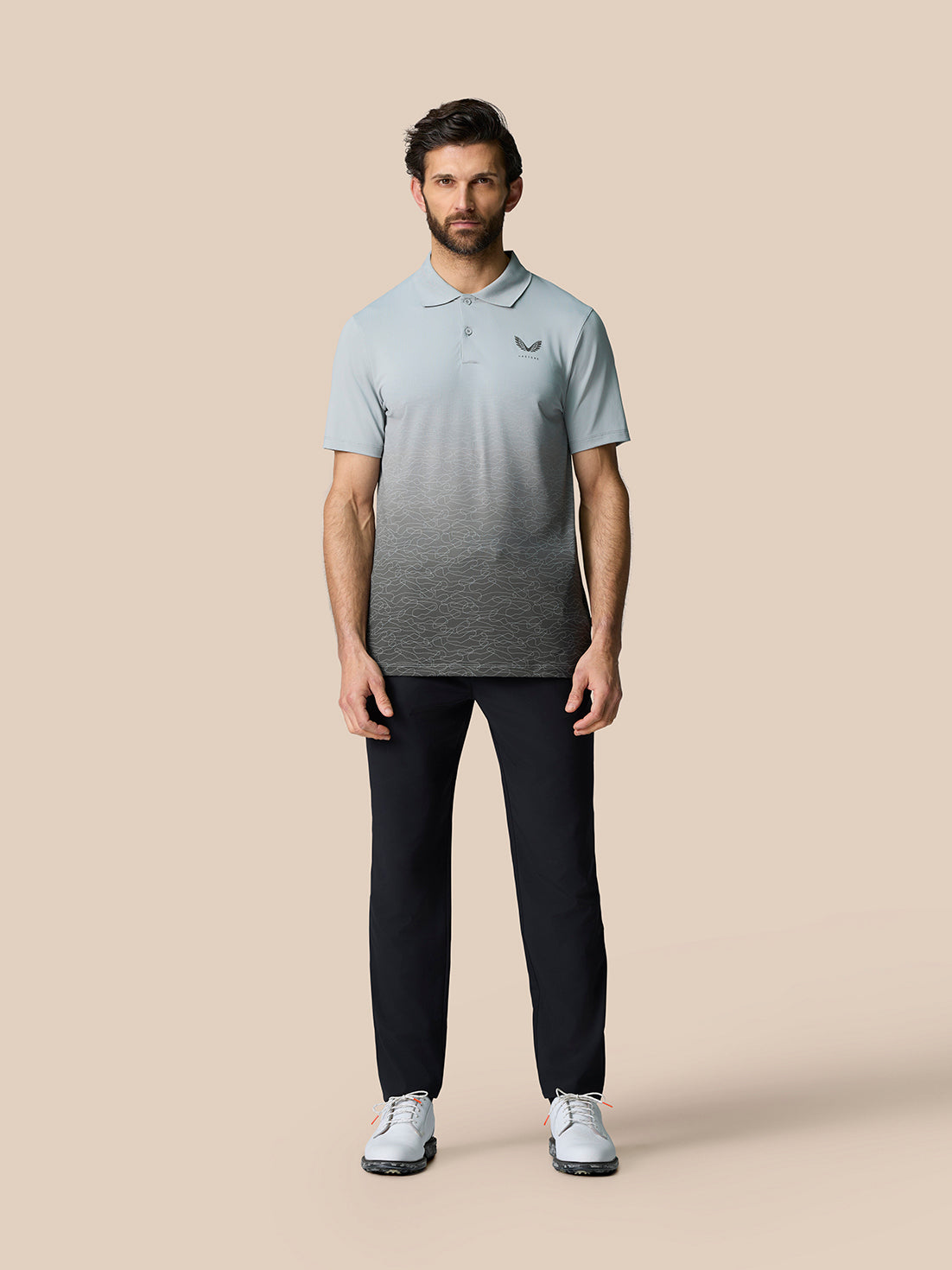 Full-body shot of a man in the Club Graphic Polo Mid Grey with gradient ombre print and Castore branding on the chest.
