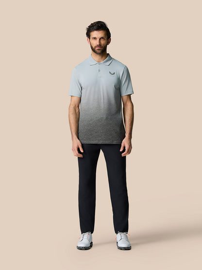 Full-body shot of a man in the Club Graphic Polo Mid Grey with gradient ombre print and Castore branding on the chest.