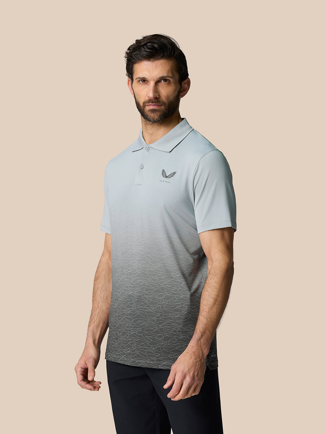 Three-quarter view of a man in the Club Graphic Polo Mid Grey featuring an allover gradient and the Castore logo on the left chest.