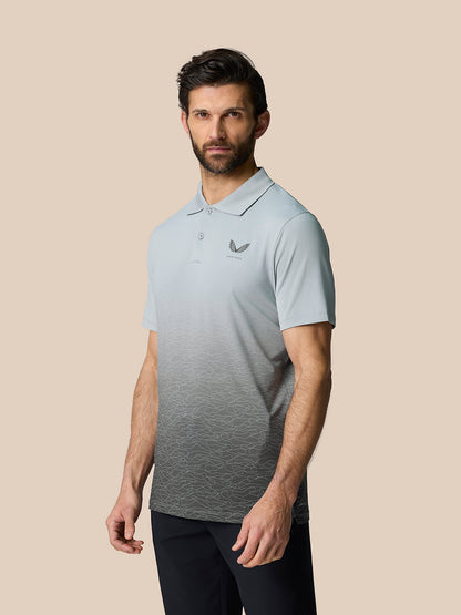 Three-quarter view of a man in the Club Graphic Polo Mid Grey featuring an allover gradient and the Castore logo on the left chest.