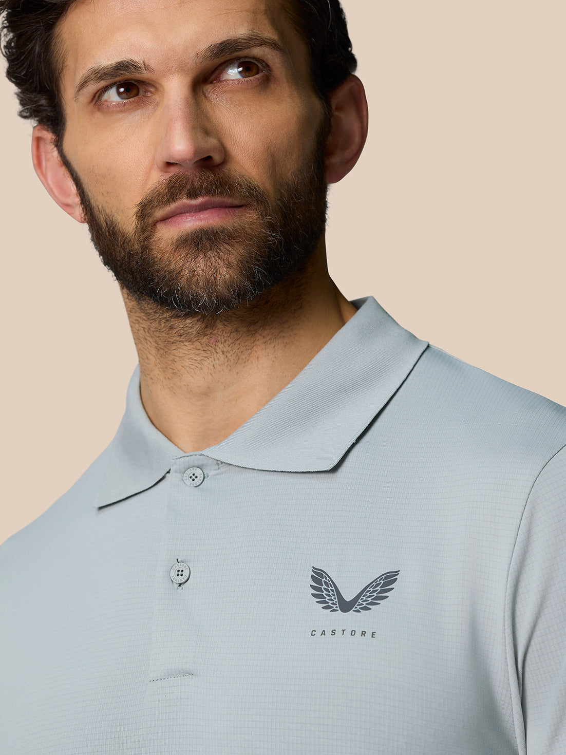 Close-up of a man wearing the Club Graphic Polo in Mid Grey with an ombre print and Castore logo on the chest.