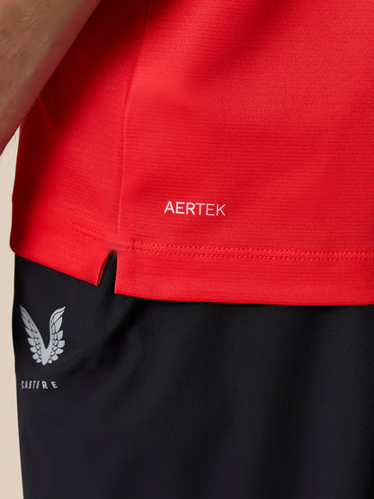 Close-up of a red AERTEK polo hem with Castore branding and wing logo on black shorts.