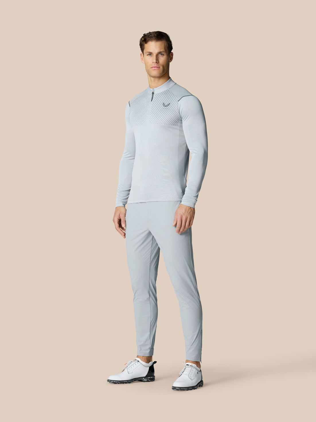 Full body shot of a man in mid grey Pinnacle LVS 1/4 Zip Top with matching pants and white golf shoes.