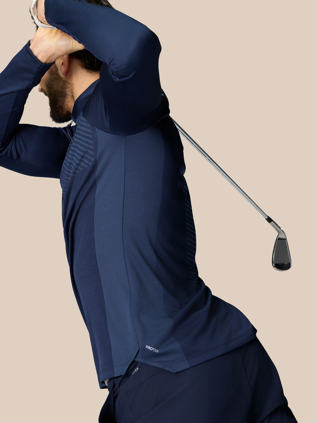 Side view of a man wearing navy Pinnacle LVS 1/4 Zip Top with side panels and a golf club positioned behind him.