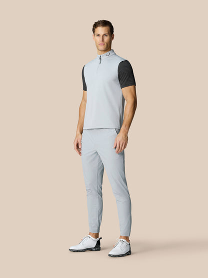 Male model wearing light grey Club Classic ½ Zip Gilet with a high neck, paired with matching trousers and white golf shoes.