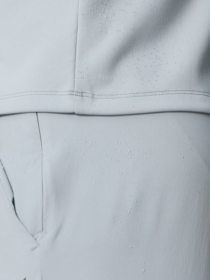 Close-up of light grey fabric with water droplets and PROTEK branding indicating the water resistant finish.