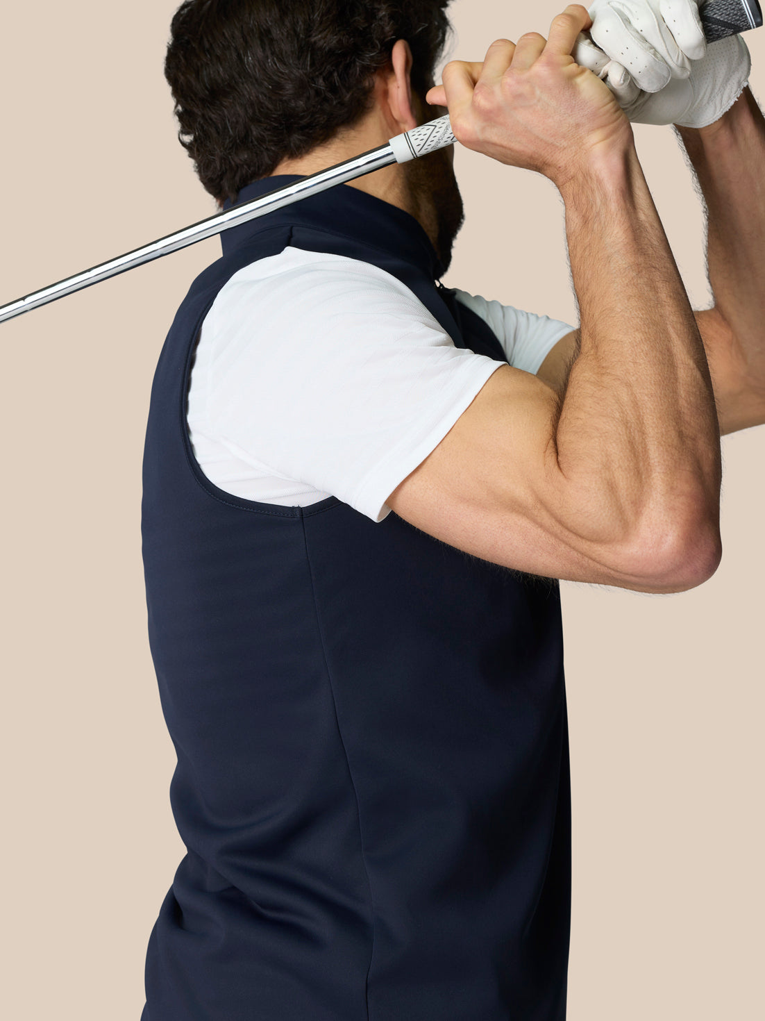 Male model wearing navy Club Classic 1/2 Zip Gilet over a white shirt, standing with a golf club