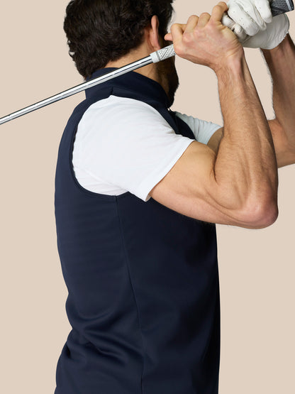 Male model wearing navy Club Classic 1/2 Zip Gilet over a white shirt, standing with a golf club