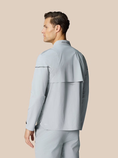 Back view of the light grey Golf Pinnacle LVS Woven Jacket on a male model showing back vent and neck Castore logo