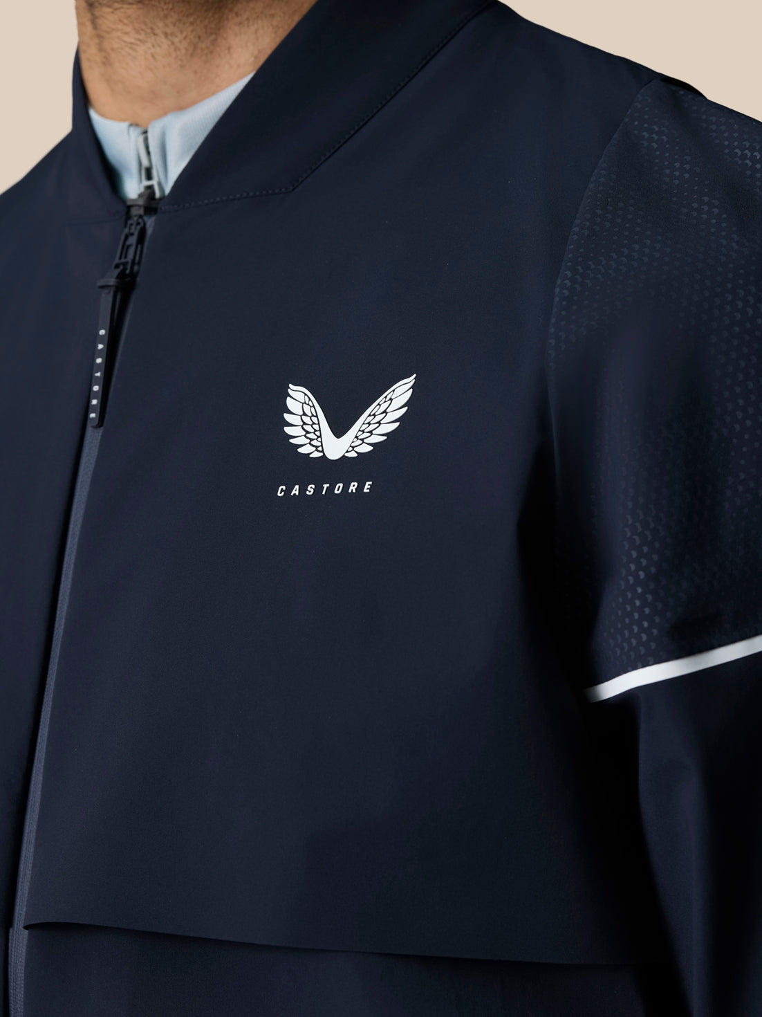Close up of left chest area with Castore logo on Midnight Navy Golf Pinnacle LVS Woven Jacket along the front zipper