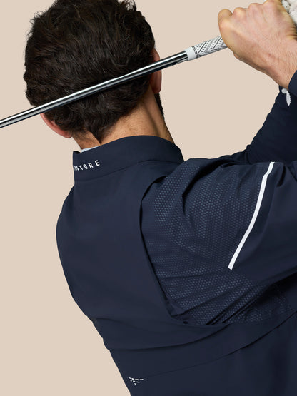Back view of a golfer wearing Midnight Navy Golf Pinnacle LVS Woven Jacket while gripping a golf club across his shoulders