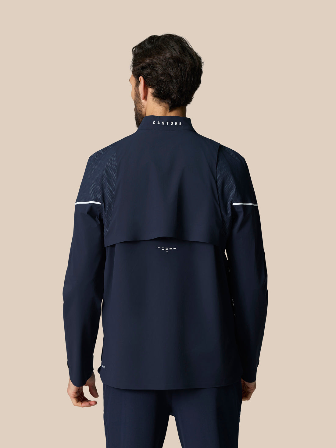 Back view of midnight navy LVS Woven Jacket showing venting panels and neck logo