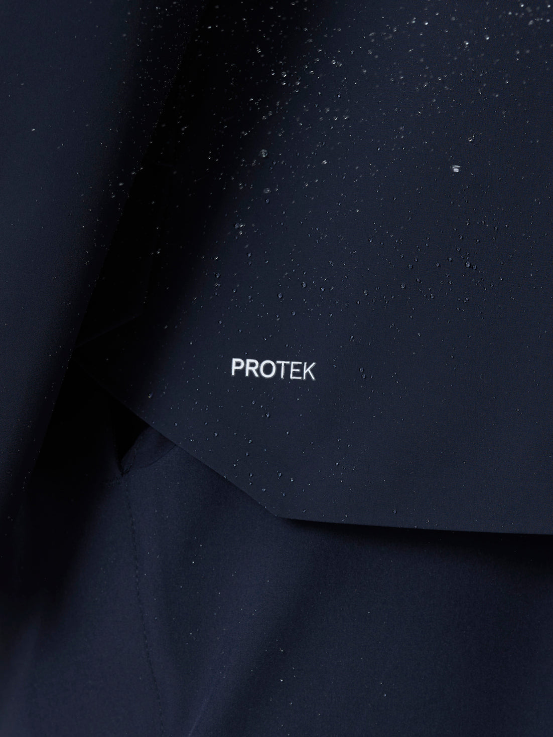 Close up of midnight navy ProTek fabric on Golf Pinnacle LVS Woven Jacket with water droplets