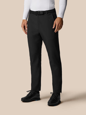 Male model wearing black Golf Pinnacle trousers with a woven belt and white top, full-length shot