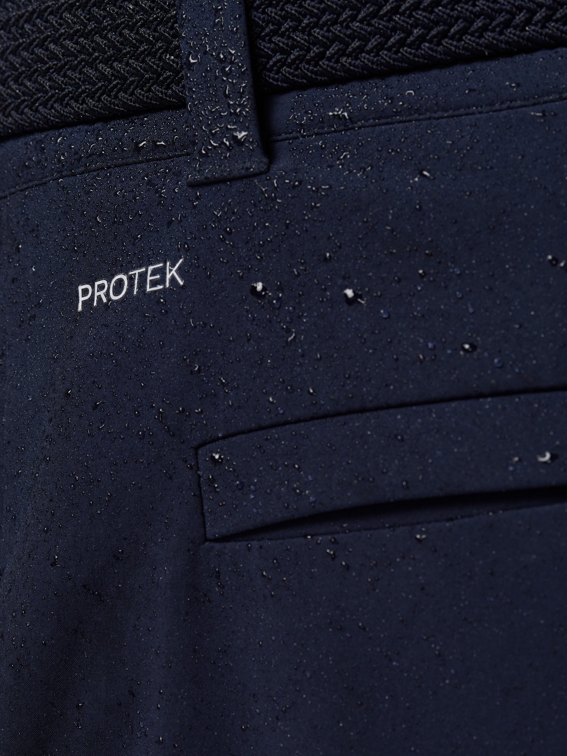 Close-up of navy ProTek water resistant fabric with a belt loop and droplets on the surface.