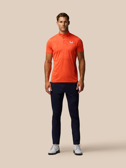 Male model wearing bright orange striped golf polo with Castore logo on left chest