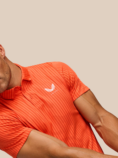 Model wearing bright orange striped Golf Pinnacle Glow Polo with Castore logo on left chest