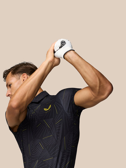 Male golfer wearing a dark printed golf polo mid swing with Castore logo on the chest.