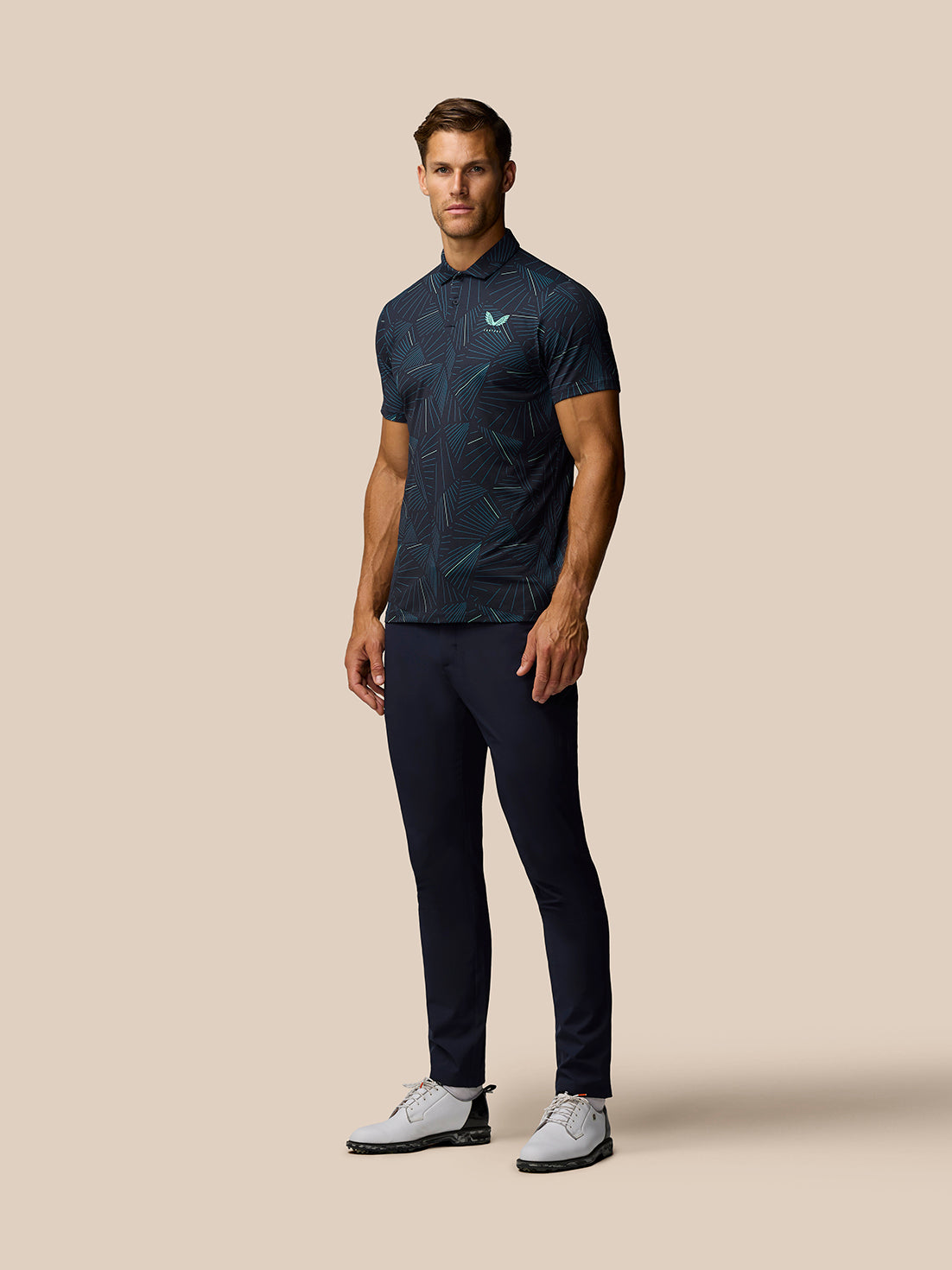Male model wearing Golf Club Swing Printed Polo in midnight navy with aqua print, full body shot