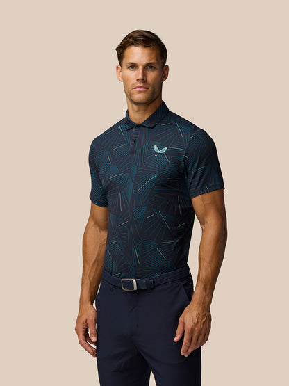 Three quarter front view of male model in midnight navy printed golf polo with aqua lines and left chest logo against beige background