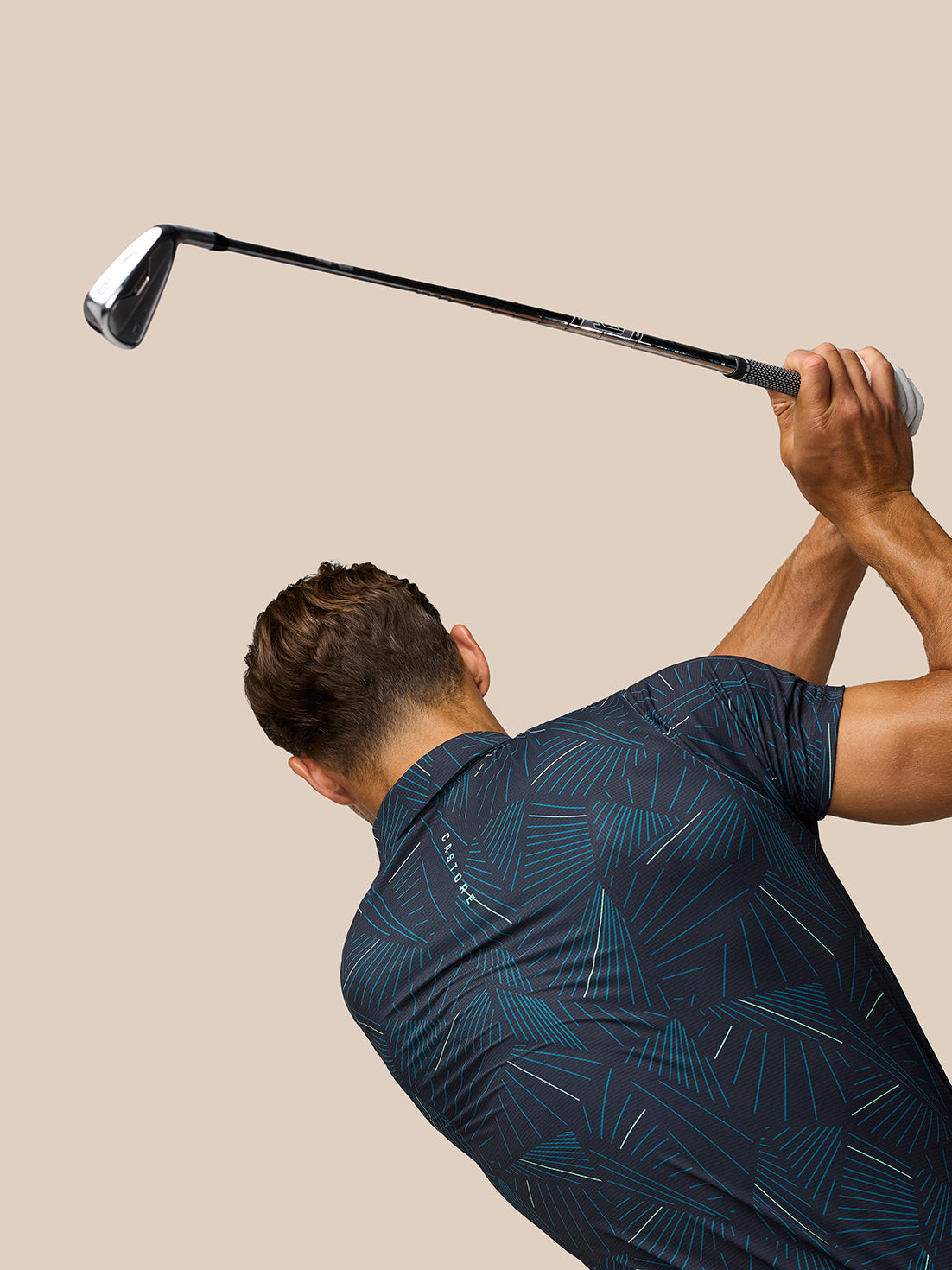 Back view of male model in Golf Club Swing Printed Polo with aqua print during a golf swing