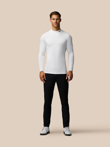 Front view of a man wearing a white Golf Club Long Sleeve Thermal Mock Neck top with black pants.