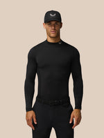 Male model wearing black Castore Golf Club thermal mock neck long sleeve top with branding at neck