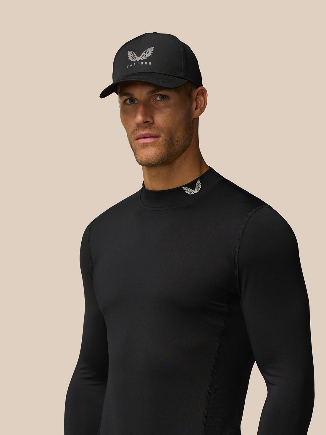 Close-up of black Castore Golf Club thermal mock neck top on male model showing branding at neck